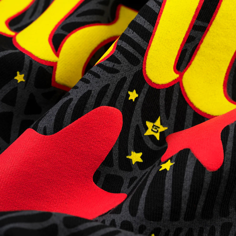 Close-up of a fabric with red, yellow, and black abstract patterns.